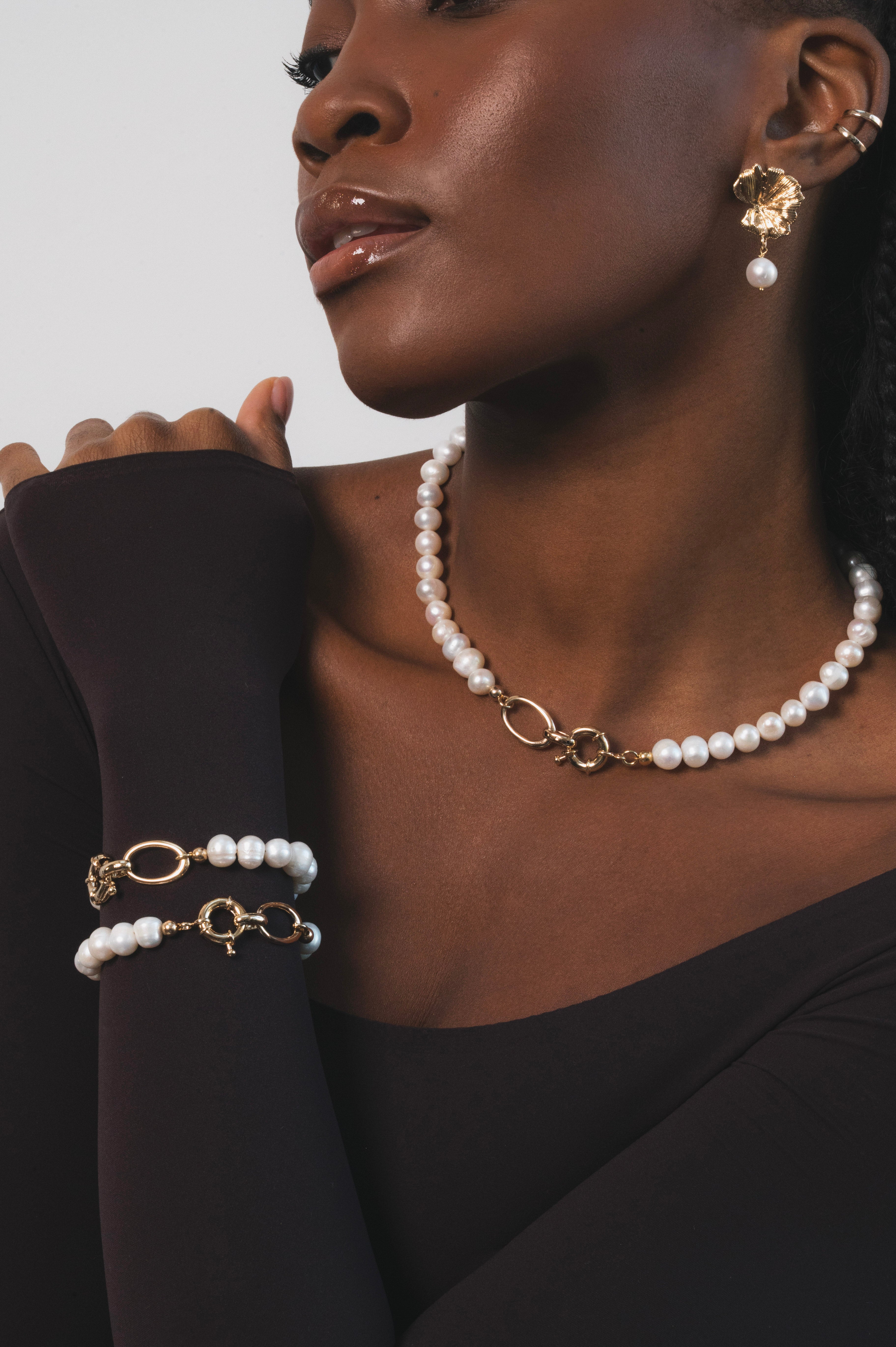Femme noire qui allie raffinement et modernité avec ses deux bracelets coordonnés en perles et maillons dorés, parfaits portés ensemble ou separement pour varier les styles. Ces perles se marient a la perfection avec les details dorés. C'est un bijou pensé pour magnifer la silhouette et apporter une touche de lumière intemporelle