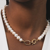 Femme noire qui porte un collier en perles d'eau douce avec des détails dorés en plaqué or. Ce collier a comme particularité un gros fermoir, ce qui fait toute la classe de ce bijou. Ce collier est rafiner, elegant et surtout unique avec ses perles d'eau douces de formes ronde.