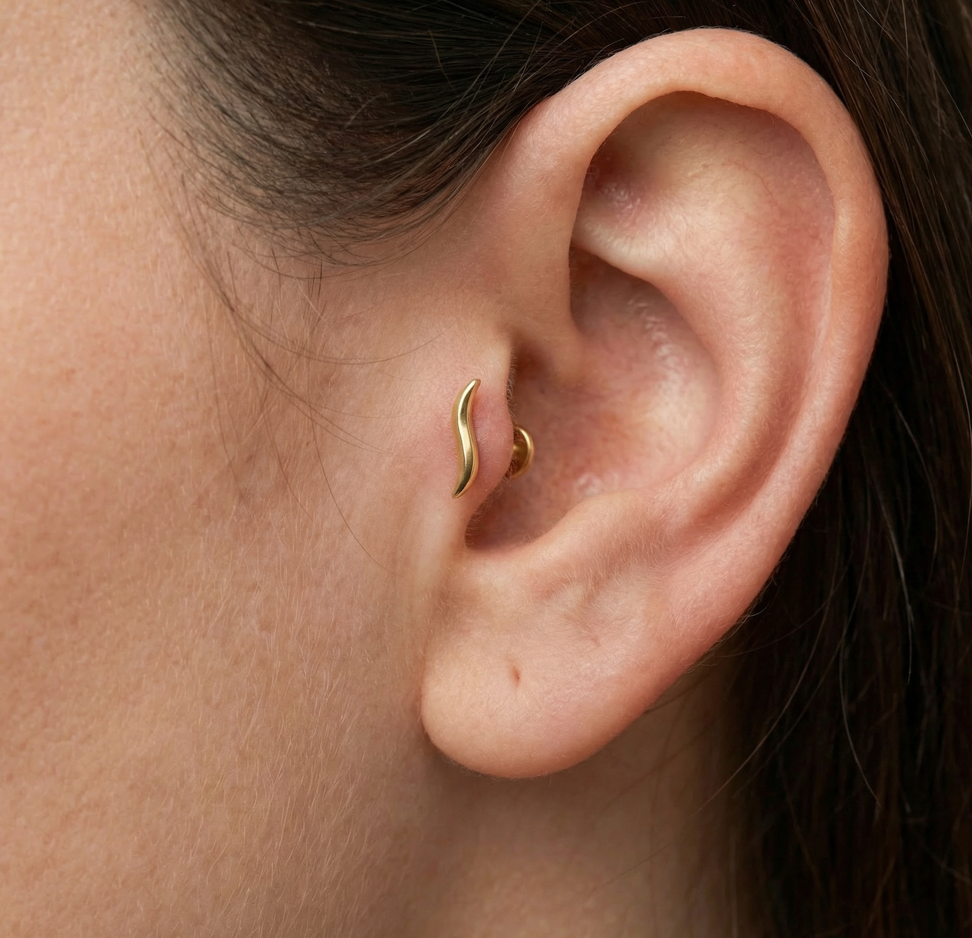 Ce piercing de tragus en titane doré allie élégance moderne et confort au quotidien. Sa forme délicatement courbée en vague épouse naturellement la ligne de l’oreille, offrant un style à la fois minimaliste et raffiné. Conçu en titane de haute qualité, il est hypoallergénique, léger et parfaitement adapté aux peaux sensibles, ce qui en fait un choix idéal pour un port prolongé ou pour une première pose.
Porté au tragus, ce bijou ajoute une touche subtile de sophistication sans être trop voyant. 