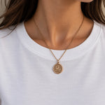 buste de jeune femme qui porte un collier doré médaille ronde inspiration piece de monnaie ancienne vintage qui représente un cavalier sur son cheval 