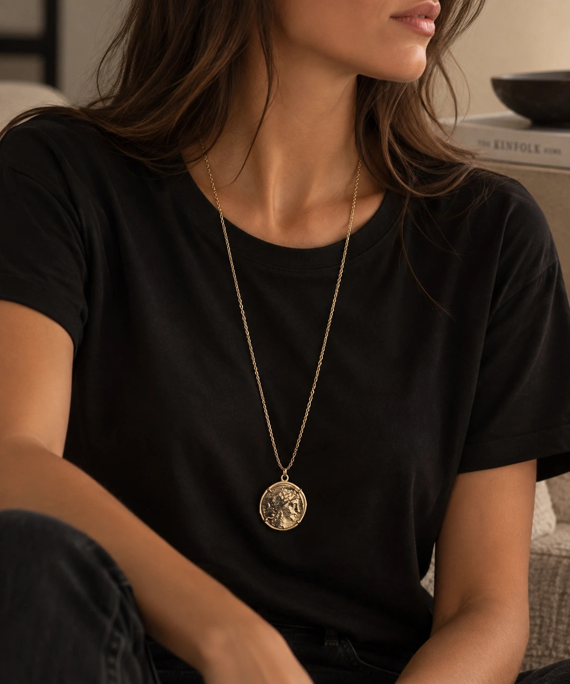 jaune femme chatain qui porte un tee shirt noir et dessus un sautoir long doré représentant Marianne visage de la république française